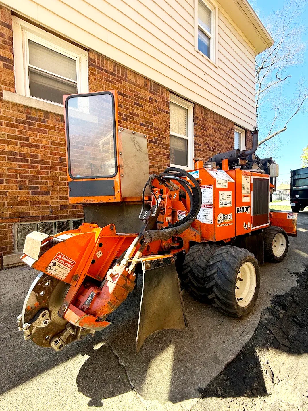 Stump grinder parked beside a brick house